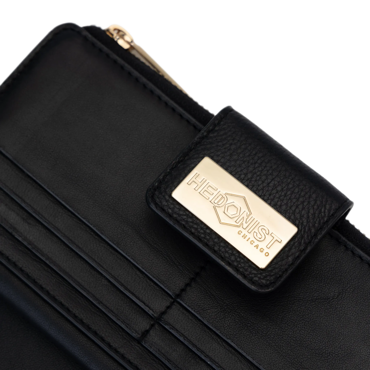 Close-up of a black leather wallet with a gold-tone metal brand plaque reading 'HEDONIST CHICAGO'.