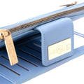 A close-up of a light blue leather wallet or clutch with gold-tone hardware, including a zipper, pull tab, and a gold-tone metal brand plaque that reads 'HEDONIST CHICAGO'.