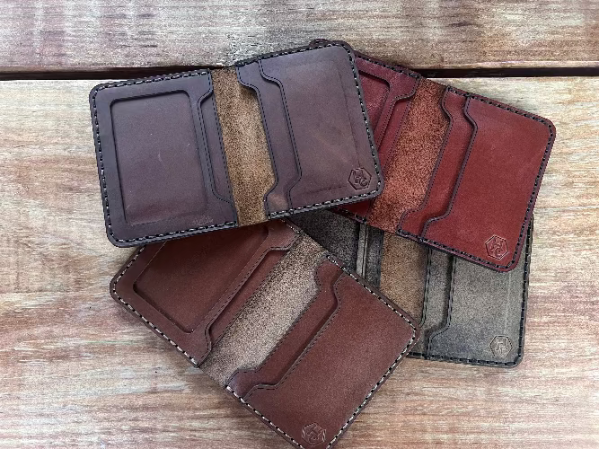 Handmade leather card holders in brown and gray on a wooden surface