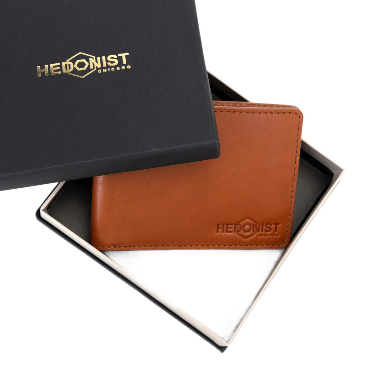 A brown leather wallet by Hedonist Chicago, displayed inside its open black presentation box with a matching lid, on a white background.