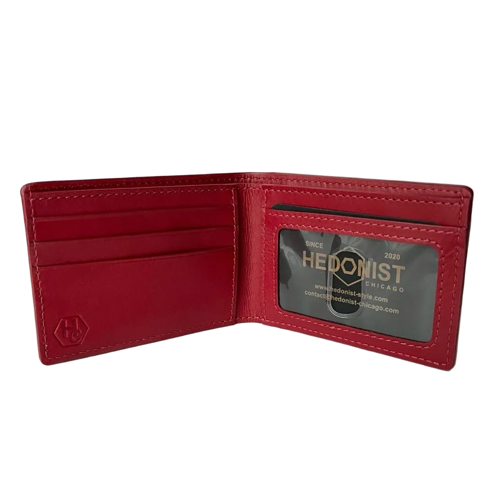 A red leather bifold wallet shown open, displaying its interior card slots and an ID window with a custom 'HEDONIST' business card insert. A debossed hexagonal logo is visible on the lower left interior corner.