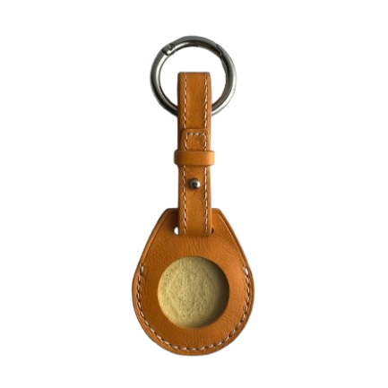A yellow leather AirTag Holder case with a circular cutout showing a textured beige insert, attached to a silver metal key ring.