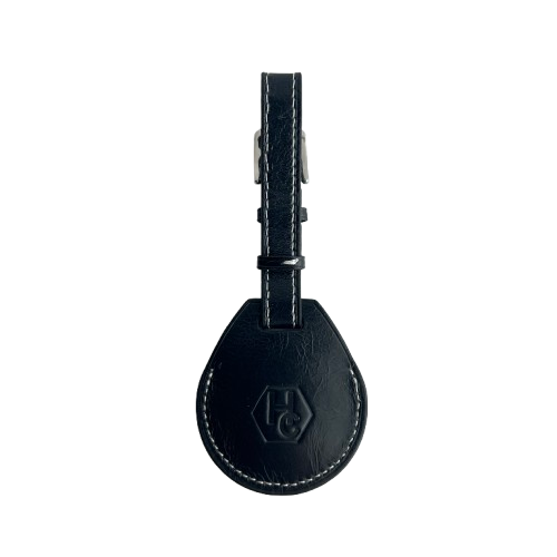 A black leather AirTag Holder with white contrast stitching and a silver metal buckle, featuring an embossed 'HC' logo on the teardrop-shaped tag