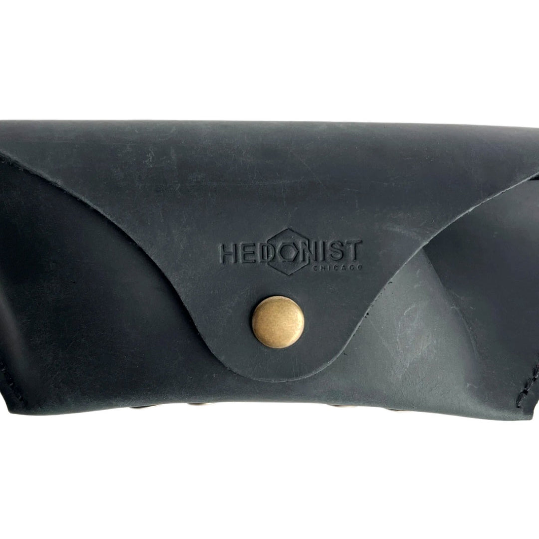 Soft Leather Eye Glasses Case in Black, closed, front view with embossed Hedonist logo and snap closure