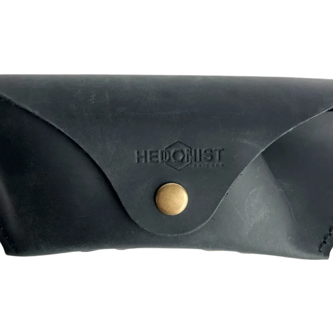 Soft Leather Eye Glasses Case in Black, closed, front view with embossed Hedonist logo and snap closure
