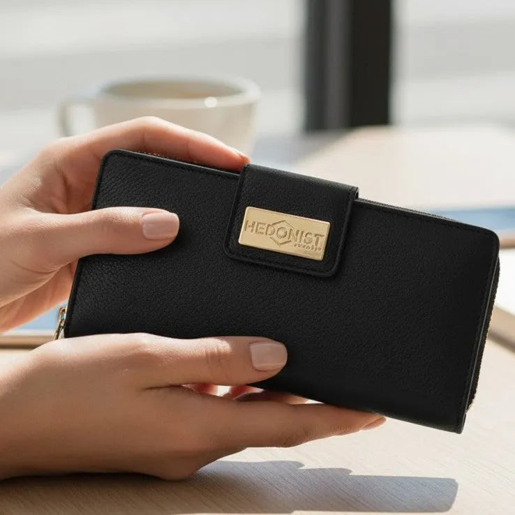 Woman holding the black pebbled leather travel wallet, blurred background