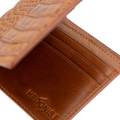 A close-up of a brown leather bifold wallet with an embossed crocodile pattern on the exterior and the brand name 'HEDONIST' debossed on the interior.