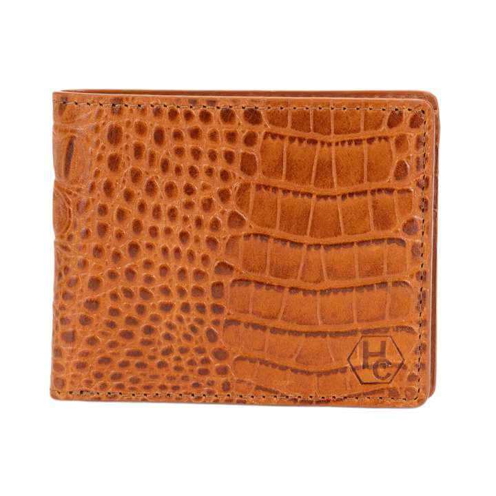A brown bi-fold wallet with a crocodile-embossed texture, featuring a small embossed 'HC' logo in the bottom right corner, set against a plain white background.