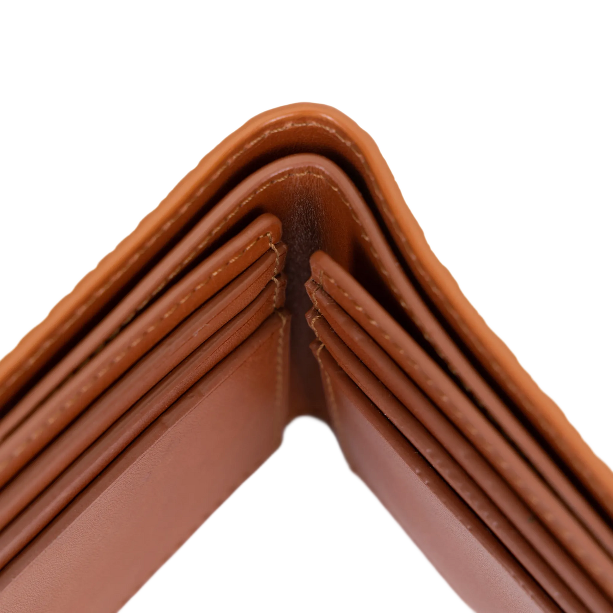 Close-up of the corner of a brown leather wallet showing the interior card slots and stitching against a white background.