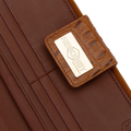 Snap-secured front flap detail on the brown croco-embossed leather travel wallet