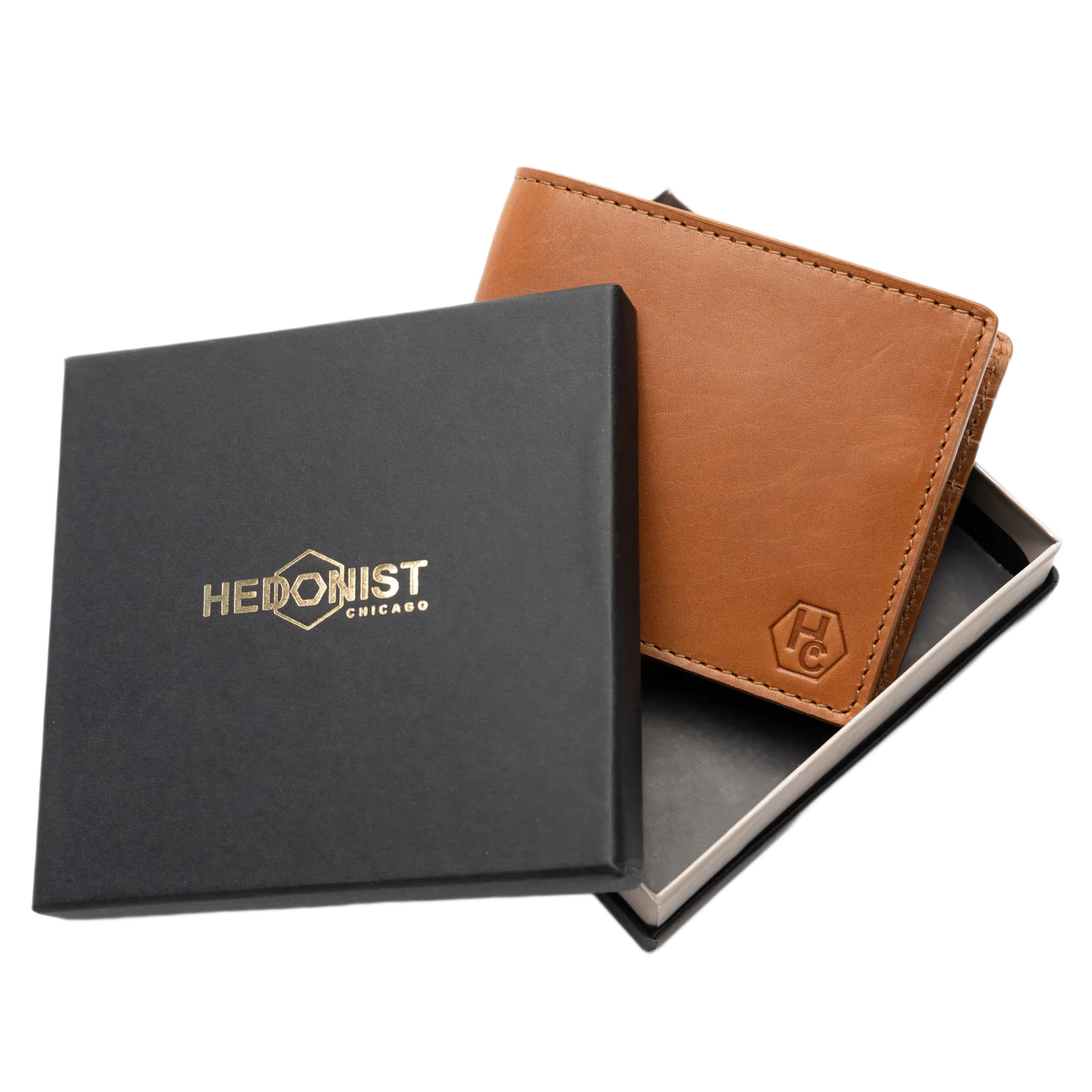 A brown leather bifold wallet displayed next to its black presentation box with gold 'HEDONIST CHICAGO' branding, on a clean white background.