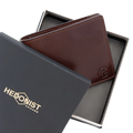A dark brown leather bi-fold wallet with an embossed 'HC' logo, presented in an open black gift box next to its black branded outer lid which features the 'HEDONIST CHICAGO' logo in gold.