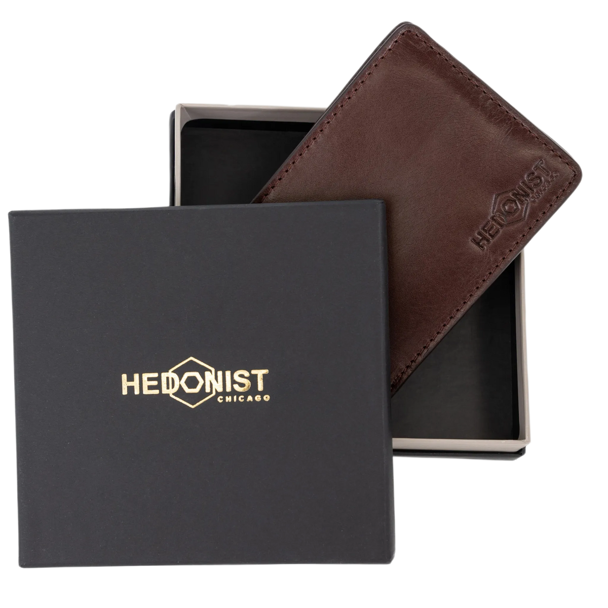 A dark brown leather wallet by Hedonist Chicago, shown partially inside its open presentation box next to its black lid, which features gold foil branding.