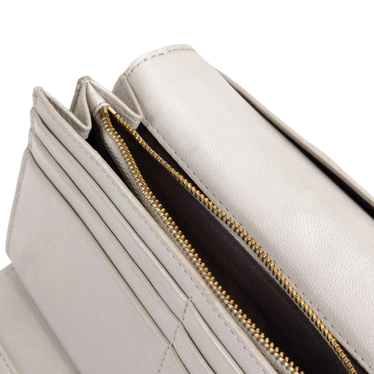 Close-up of gray leather trifold wallet card slots, gold zipper, and interior lining