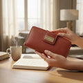 Woman holding the large red pebbled leather travel wallet, blurred background