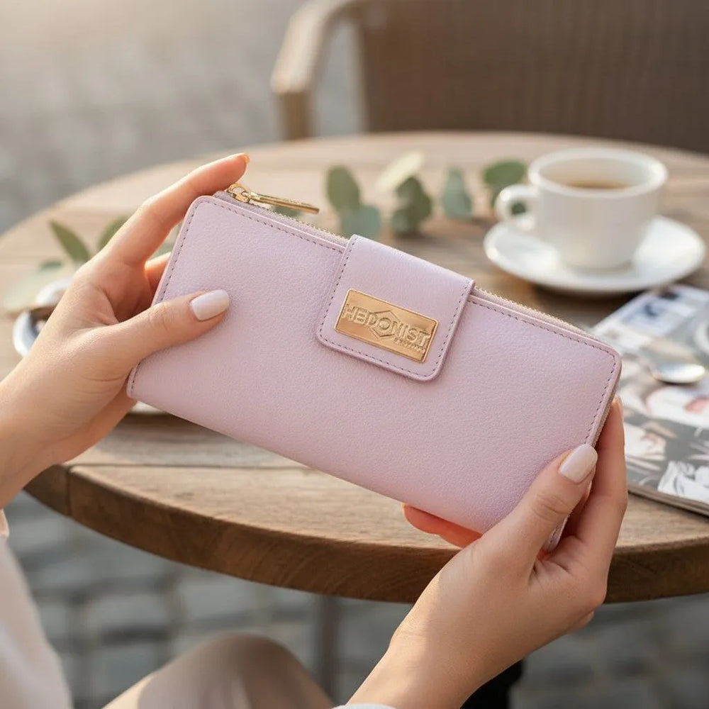 Woman holding the pink pebbled leather travel wallet with blurred cafe background