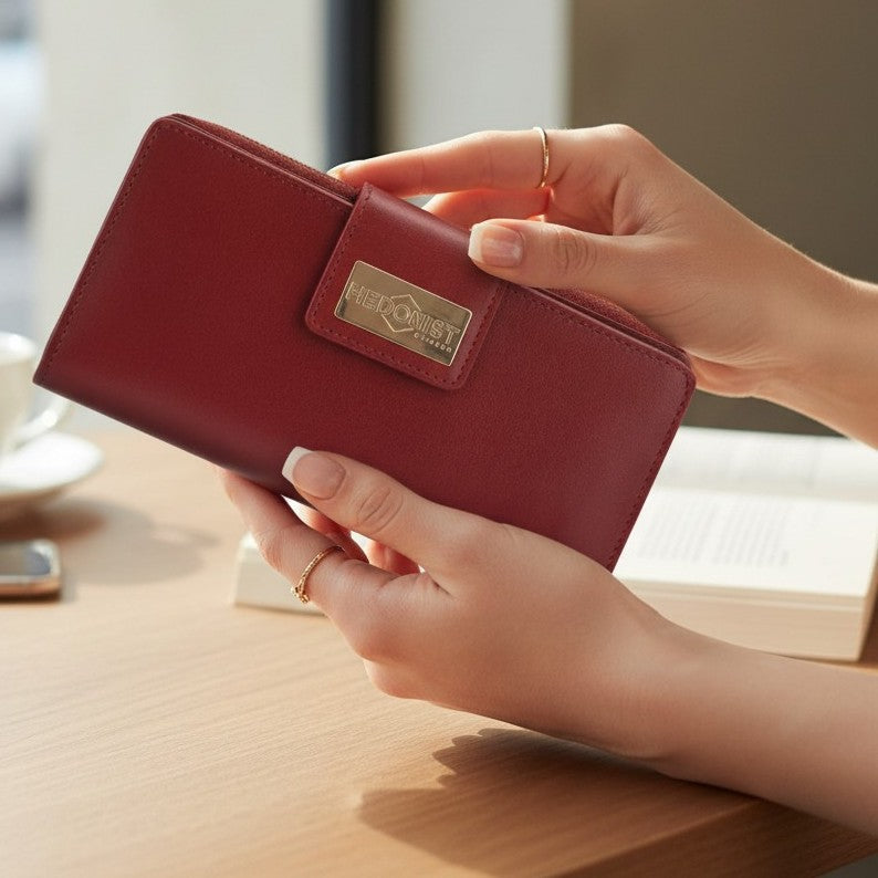 Woman holding the long red leather wallet on a wooden surface