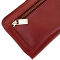 Close-up of gold-tone zipper pull with engraved logo on the long red leather wallet