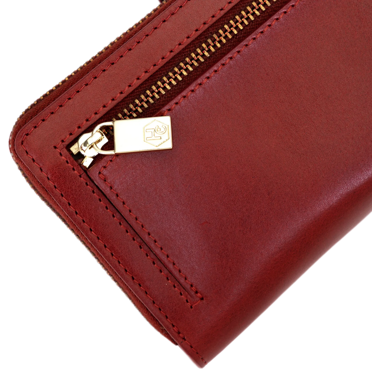 Close-up of gold-tone zipper pull with engraved logo on the long red leather wallet