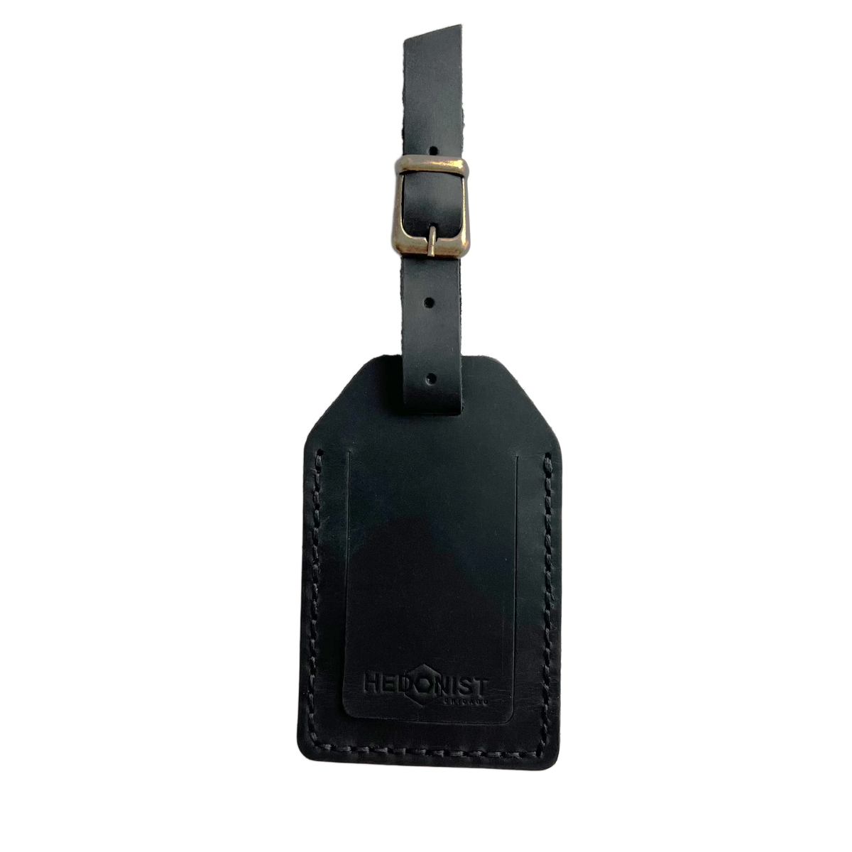 Black full-grain leather luggage tag with brass buckle strap, embossed Hedonist Chicago logo on the front, shown on an off-white background.