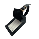 Black full-grain leather luggage tag with matching leather strap and brass buckle, shown on a light gray background.
