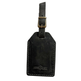 Black washed full-grain leather luggage tag with brass buckle strap, embossed Hedonist Chicago logo near the bottom, shown on a light background.