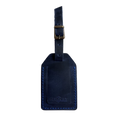 Navy blue full-grain leather luggage tag with matching strap and brass buckle, blue stitching, embossed Hedonist Chicago logo on the front, shown on an off-white background.