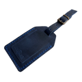 Navy blue full-grain leather luggage tag with bright blue stitching and brass buckle, embossed Hedonist Chicago logo on the front, shown on a light gray background.