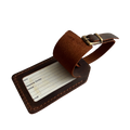 Brown full-grain leather luggage tag with matching adjustable strap and brass buckle, shown on a light gray background.