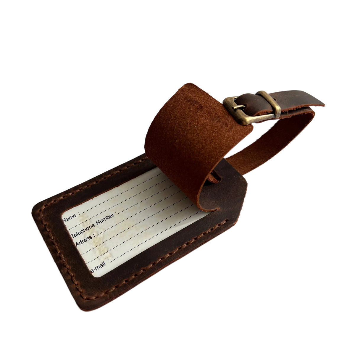 Brown full-grain leather luggage tag with matching adjustable strap and brass buckle, shown on a light gray background.