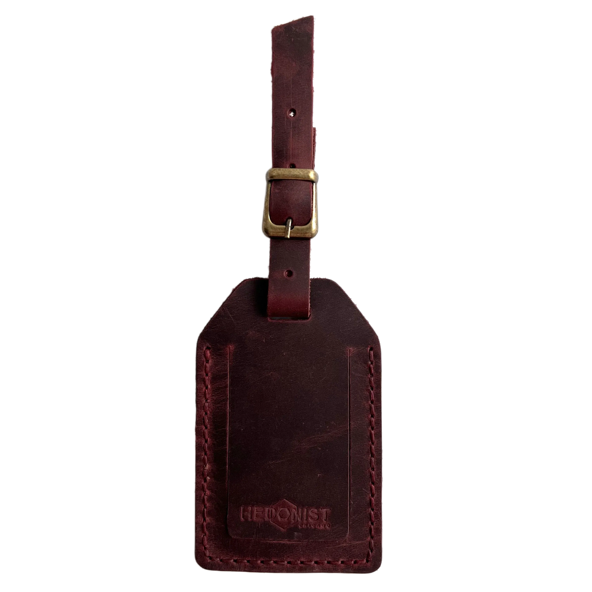 Burgundy full-grain leather luggage tag with brass buckle, embossed Hedonist Chicago logo near the bottom, shown on a white background.