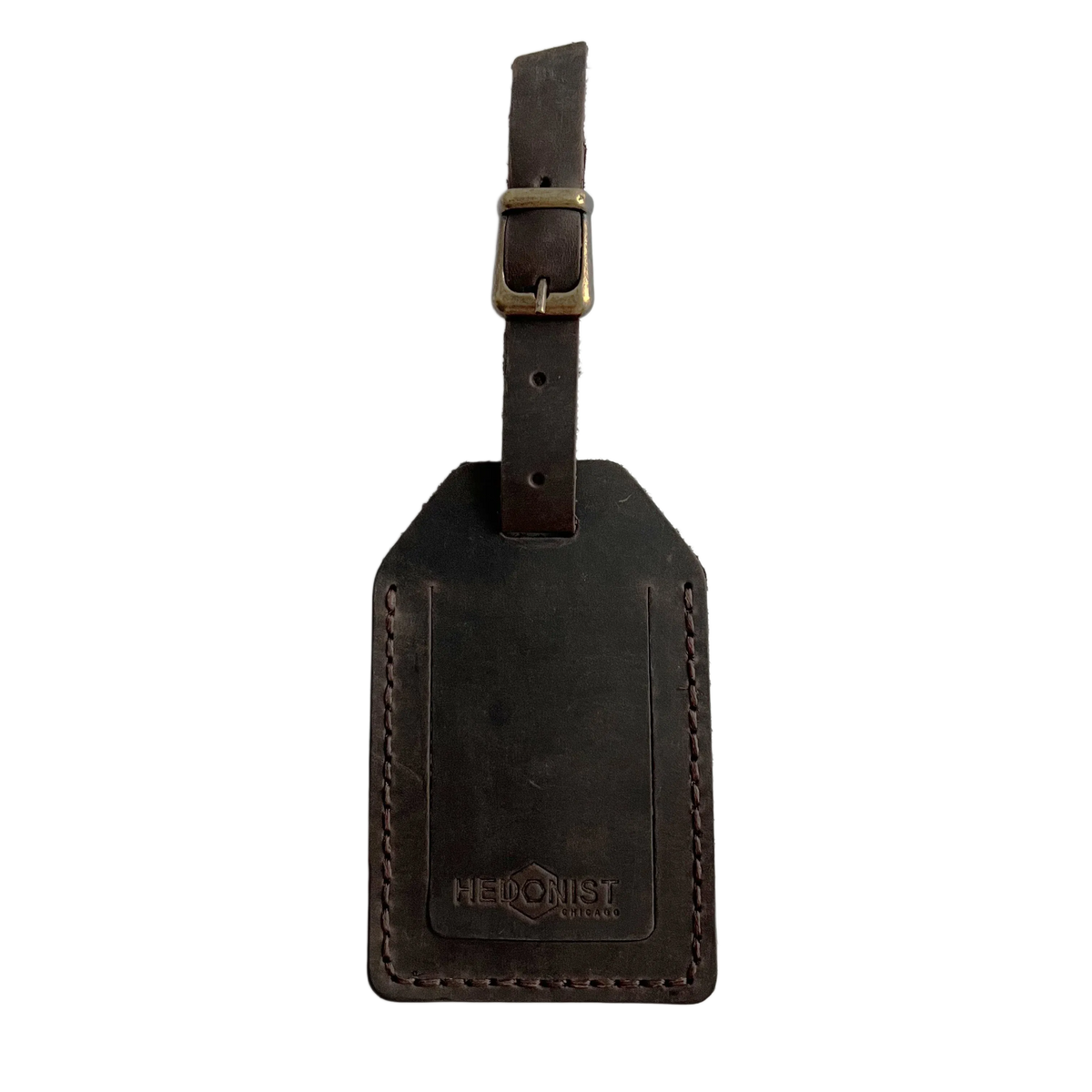Dark brown full-grain leather luggage tag with matching leather strap and brass buckle, embossed Hedonist Chicago logo on the front, shown on a light gray background.
