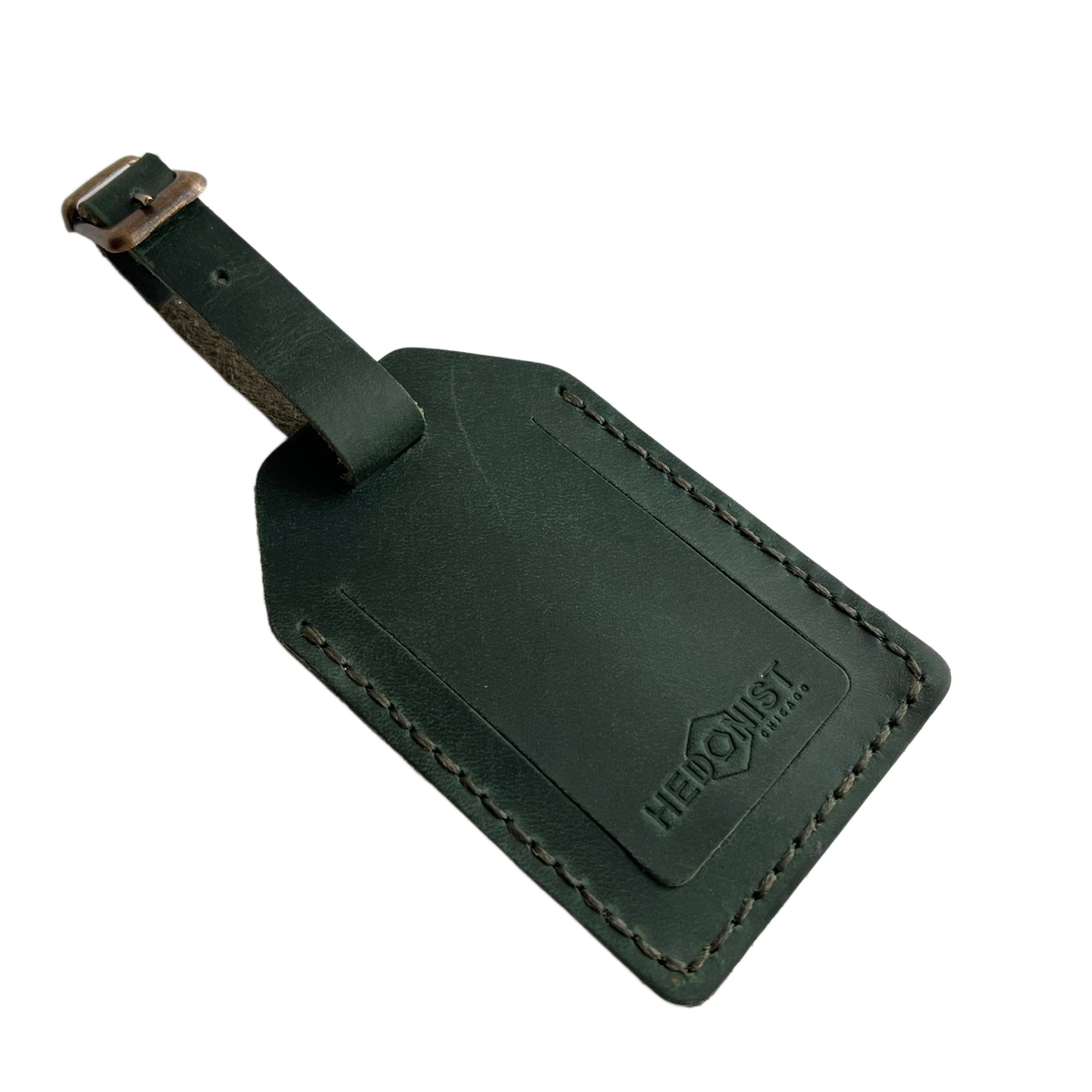 Green full-grain leather luggage tag with matching leather strap and brass buckle, visible contrast stitching, embossed Hedonist Chicago logo on the front.