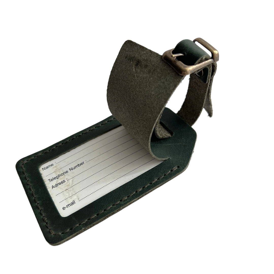 Green full-grain leather luggage tag with matching adjustable strap and brass buckle, shown on a white background.