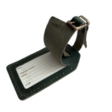 Green full-grain leather luggage tag with matching adjustable strap and brass buckle, shown on a white background.