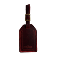 Red full-grain leather luggage tag with brass buckle and strap, embossed Hedonist Chicago logo on the front, shown on a white background.