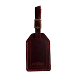Red full-grain leather luggage tag with brass buckle and strap, embossed Hedonist Chicago logo on the front, shown on a white background.
