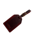 Red full-grain leather luggage tag with brass buckle, embossed Hedonist Chicago logo on the front, shown on a light gray background.