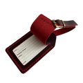 Red full-grain leather luggage tag with matching adjustable strap and brass buckle, shown on a light background.