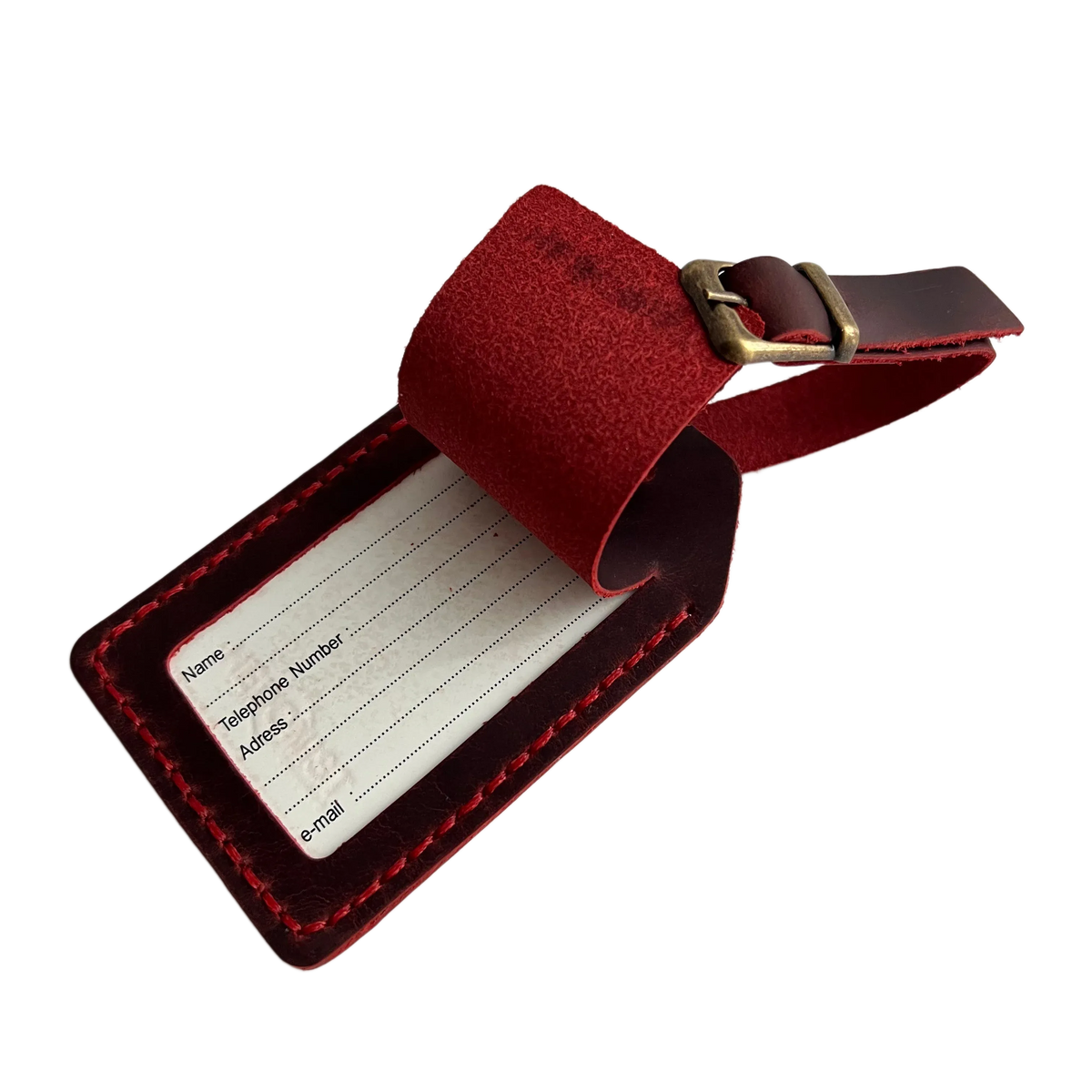 Red full-grain leather luggage tag with matching adjustable strap and brass buckle, shown on a light background.