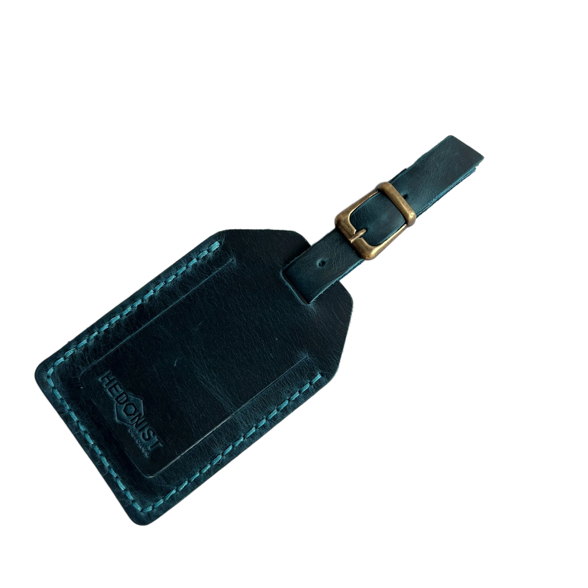 Teal full-grain leather luggage tag with brass buckle and matching stitching, embossed Hedonist Chicago logo on the front, shown on a light gray background.