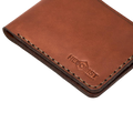 Handmade medium brown leather bifold wallet, close-up of monogram branding