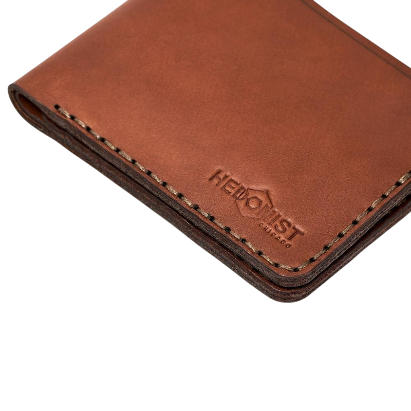 Handmade medium brown leather bifold wallet, close-up of monogram branding