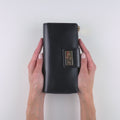 Stylish black zip-around travel wallet for women shown with travel documents