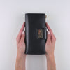Stylish black zip-around travel wallet for women shown with travel documents
