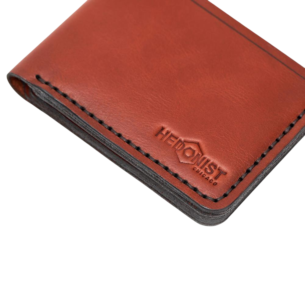 Handmade red brick leather bifold wallet, close-up of monogram branding