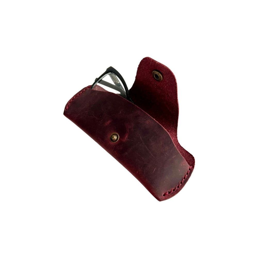 Small Soft Leather Eye Glasses Case in Burgundy, angled view with black-framed eyeglasses tucked inside