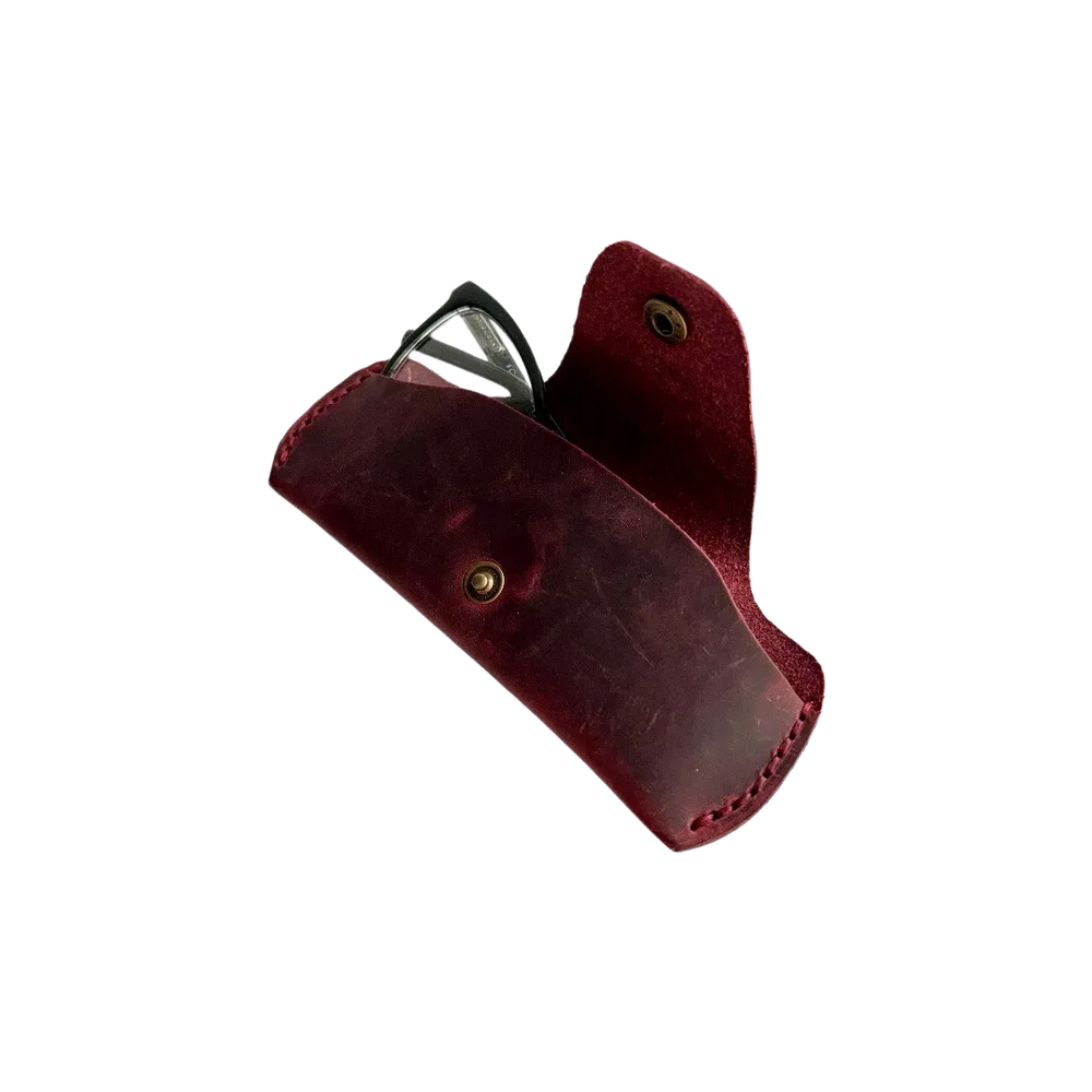 Small Soft Leather Eye Glasses Case in Burgundy, angled view with black-framed eyeglasses tucked inside