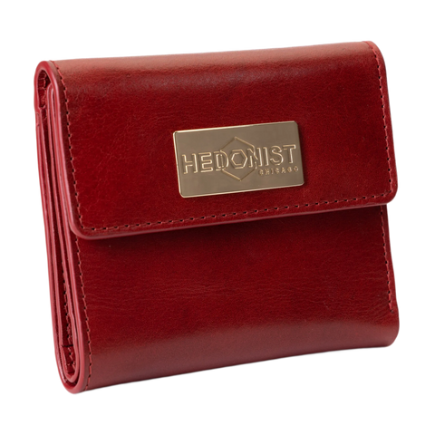 A red leather bi-fold wallet with a gold-tone metal brand plaque on the front flap.