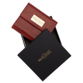 A red leather wallet with a gold-tone logo plaque, shown partially inside a black presentation box with a matching gold HEDONIST logo.